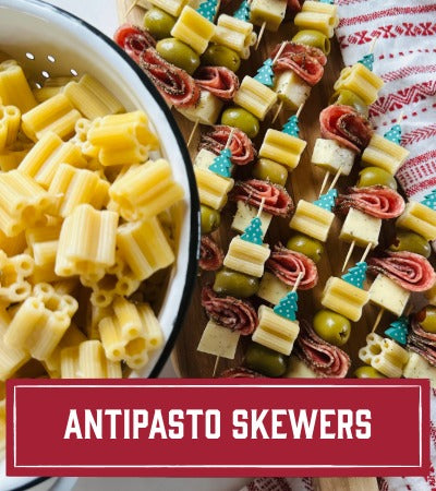 Skewers with pasta, salami, cheese. and olives next to a bowl of quattrotini pasta. With Text overlay "Antipasto Skewers"