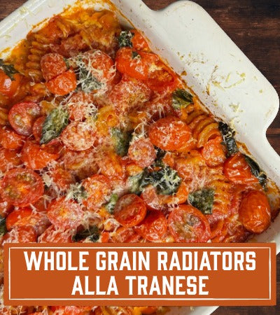 Sfoglini Pasta Recipe: Baked dish with tomatoes and basil in a white dish on a wooden surface, with text 'Whole Grain Radiators Alla Tranese'.