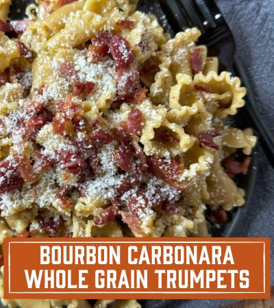 Sfoglini Pasta Recipe: Pasta dish with bacon and parmesan cheese on a plate,. with text ovrlay 'Bourbon Carbonara Whole Grain Trumpets'.