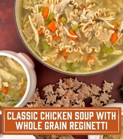 Sfoglini Pasta Recipe: Chicken soup with whole grain reginetti noodles in a pot and bowl on a red background. With text overlay "Classic Chicken soup with whole grain reginetti "