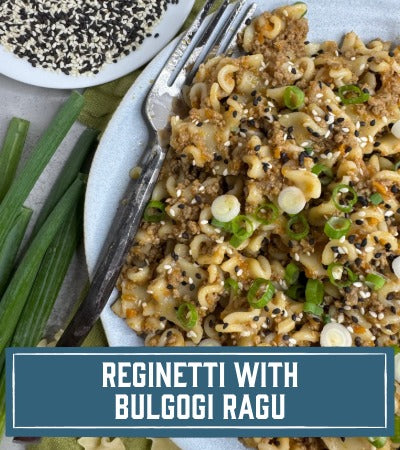 Sfoglini Pasta Recipe: Pasta dish with bulgogi meat sauce on a plate with a fork, surrounded by green onions. With text overlay "Reginetti with Bulgogi Ragu"