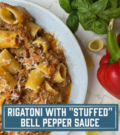 Sfoglini Pasta Recipe: Rigatoni pasta dish with stuffed bell pepper sauce on a plate, surrounded by basil and a red bell pepper. with text overlay "Rigatoni with 'Stuffed" Bell Pepper Sauce"