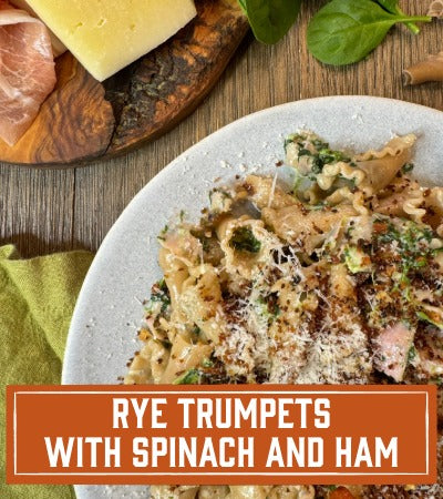 Sfoglini Pasta Recipe: Pasta dish with spinach and ham on a wooden table, featuring text 'Rye Trumpets with Spinach and Ham'.