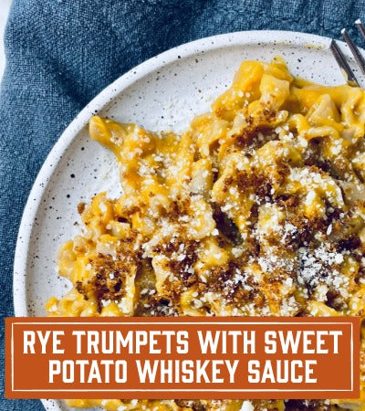 Sfoglini Pasta Recipe: Plate of rye trumpets with sweet potato whiskey sauce on a speckled plate with a blue napkin. With text overlay "Rye Trumpets with Sweet Potato Whiskey Sauce"