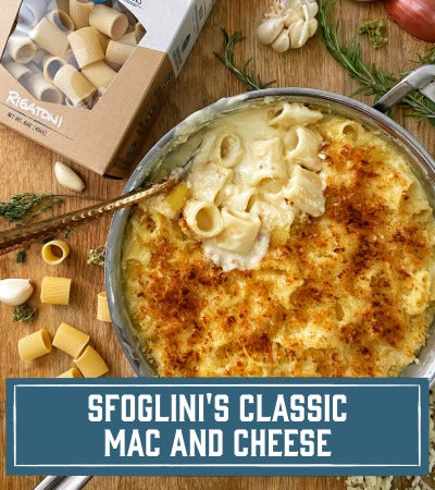 Sfoglini Pasta Recipe: Mac and cheese dish with Sfoglini Rigatoni pasta packaging on a wooden board. with text overlay "Sfoglini's Classic Mac and Cheese"