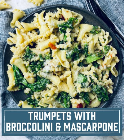 Sfoglini Pasta Recipe: Pasta dish with broccolini and mascarpone on a black plate, text overlay 'Trumpets with Broccolini & Mascarpone'.