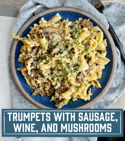 Sfoglini Pasta Recipe: Pasta dish with sausage, wine, and mushrooms on a blue plate with text overlay "Trumpets with Sausage, wine, and Mushrooms"