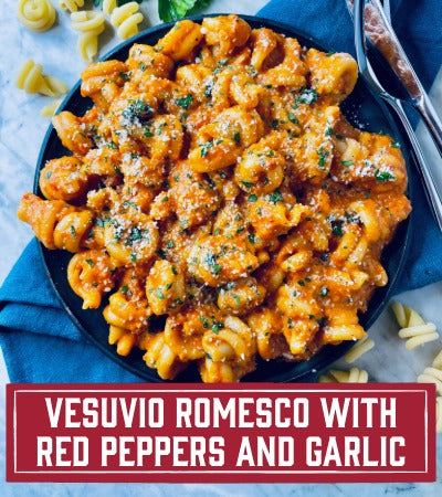 Sfoglini Pasta Recipe: Pasta dish with red peppers and garlic on a black plate, labeled 'Vesuvio Romesca with Red Peppers and Garlic'.