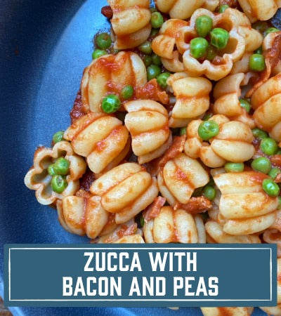 Sfoglini Pasta Recipe:  Pasta dish with bacon and peas on a blue plate. With text overlay "Zucca with Bacon and peas"