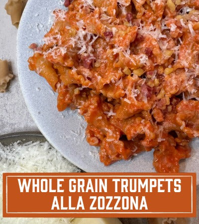 Plate of pasta with red sauce and parmesan cheese, labeled 'Whole Grain Trumpets Alla Zozzona'.