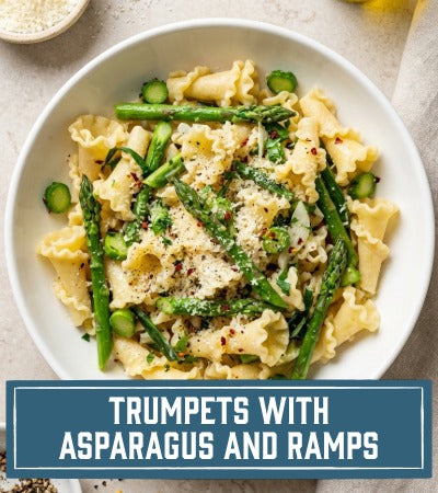Pasta dish with asparagus and ramps in a white bowl on a light background. With text "Trumpets with Asparagus and Ramps"