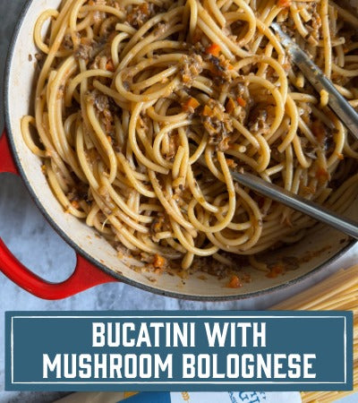 Sfoglini Pasta Recipe: Bucatini with Mushroom Bolognese. Long noodles in a red pot with sauce.