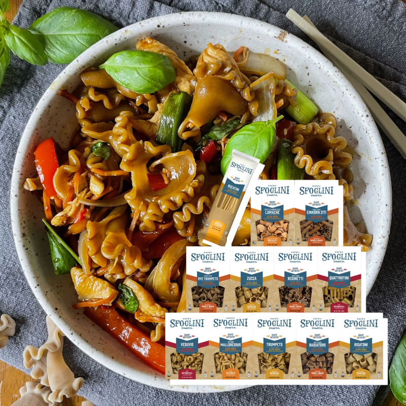 Pasta dish with vegetables and Sfoglini pasta packages on a gray surface